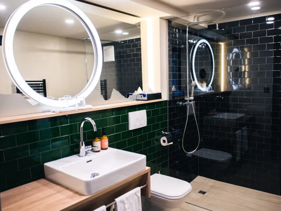 Salle de bains moderne, carrelage sombre, vasque et miroir rond