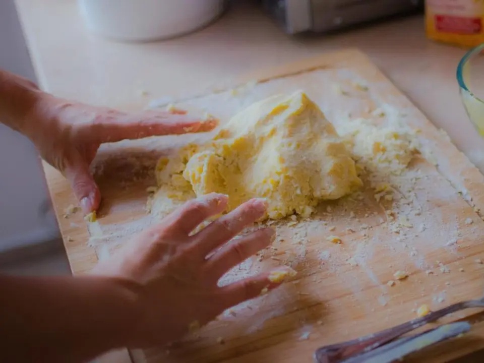 Mains pétrissant une pâte sur un plan de travail